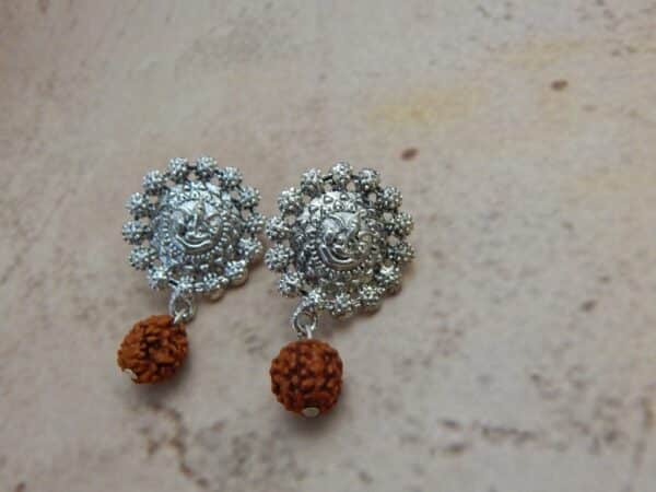 A pair of oxidised silver-toned earrings with a Ganesha motif stud and a single rudraksha bead hanging below