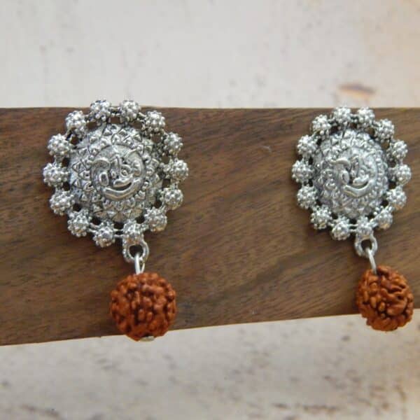 A pair of oxidised silver-toned earrings with a Ganesha motif stud and a single rudraksha bead hanging below