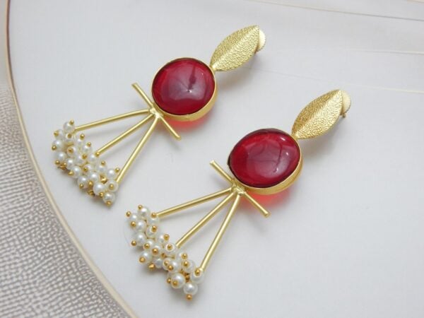 A pair of gold-tone artistic earrings with a leaf stud, a large round red stone, and a cluster of pearl dangles.