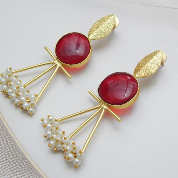 A pair of gold-tone artistic earrings with a leaf stud, a large round red stone, and a cluster of pearl dangles.
