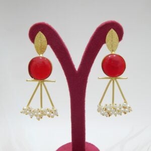 A pair of gold-tone artistic earrings with a leaf stud, a large round red stone, and a cluster of pearl dangles.