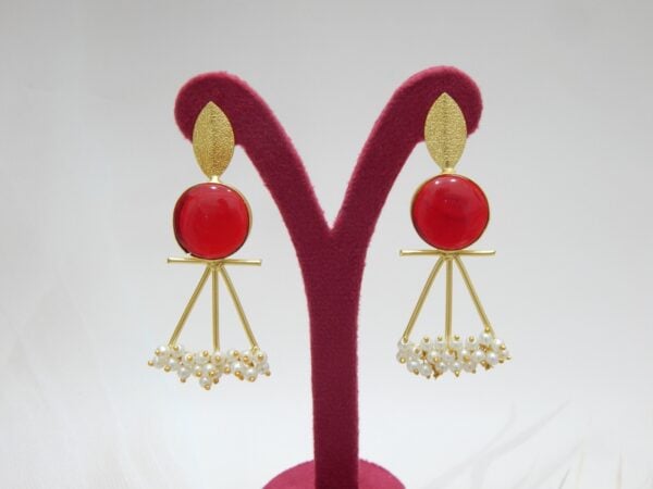 A pair of gold-tone artistic earrings with a leaf stud, a large round red stone, and a cluster of pearl dangles.