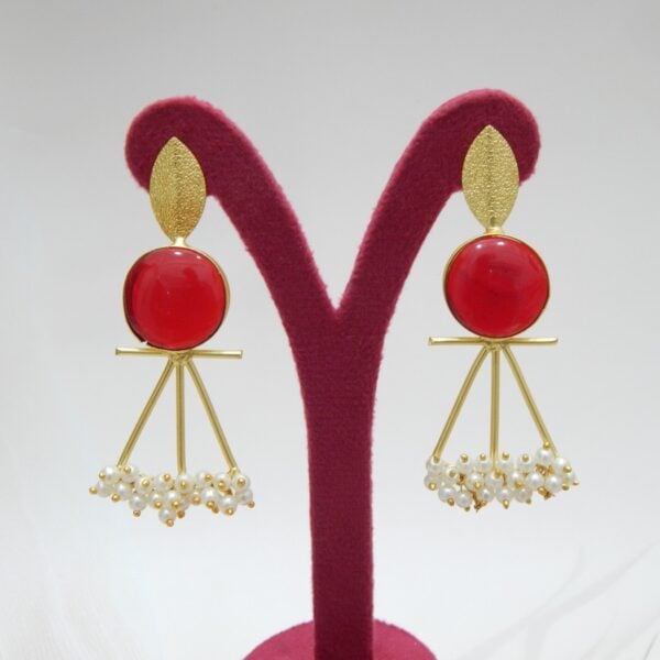 A pair of gold-tone artistic earrings with a leaf stud, a large round red stone, and a cluster of pearl dangles.