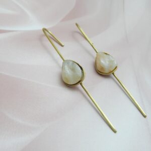 A pair of gold-tone long drop earrings with a natural-looking milky white/peach teardrop stone set on a thin bar.