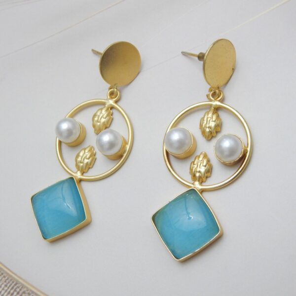 A pair of gold-tone geometric dangle earrings with a circle frame, white pearls, and a large square-shaped aqua blue stone.