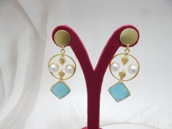 A pair of gold-tone geometric dangle earrings with a circle frame, white pearls, and a large square-shaped aqua blue stone.