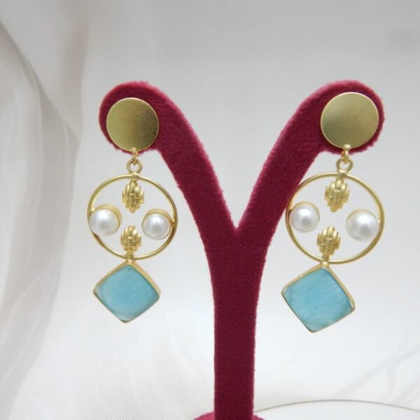 A pair of gold-tone geometric dangle earrings with a circle frame, white pearls, and a large square-shaped aqua blue stone.