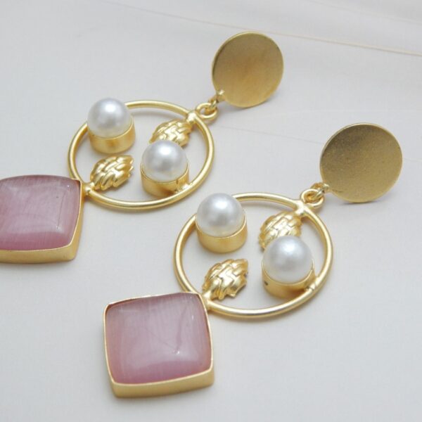 A pair of gold-tone geometric dangle earrings with a circle frame, white pearls, and a large square-shaped blush pink stone.