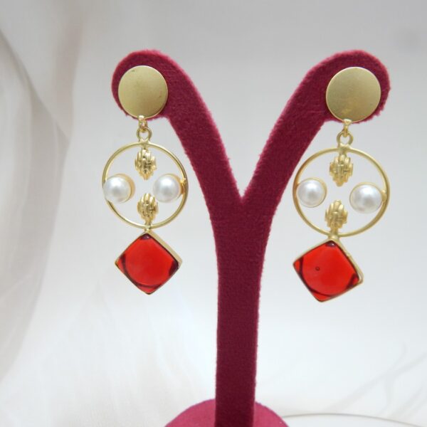 A pair of gold-tone geometric dangle earrings with a circle frame, white pearls, and a large square-shaped blue stone.