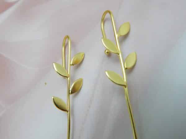 Gold-tone minimalist leaf earrings with four leaves along a slim bar and hook ear wire