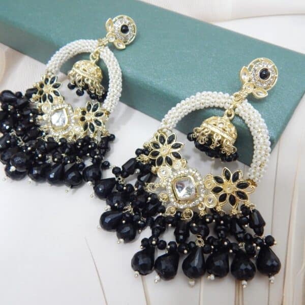 A pair of gold Kundan jhumka earrings with a half-moon design and black beaded drops