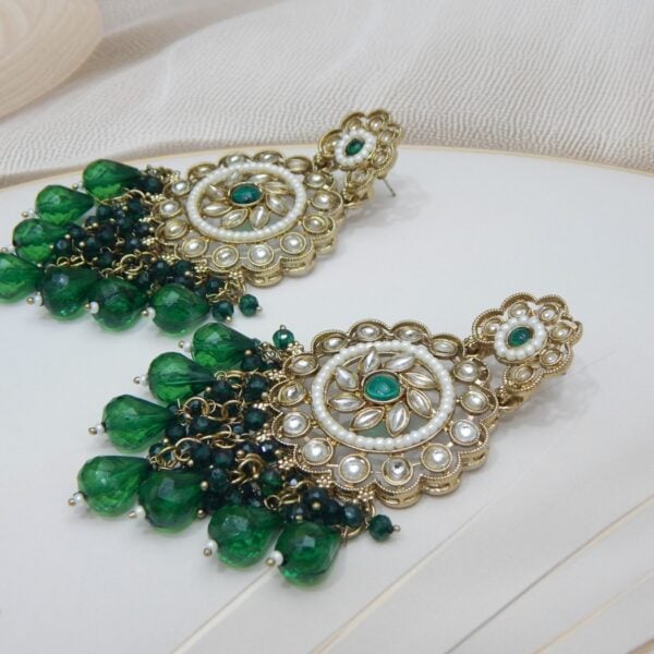 Navratri Green Jewellery - Royal Reflection DS A pair of large, traditional dangle earrings with a central oval stone, intricate work, a halo of small pearls, and a fan of dangling dark colored colored beads.