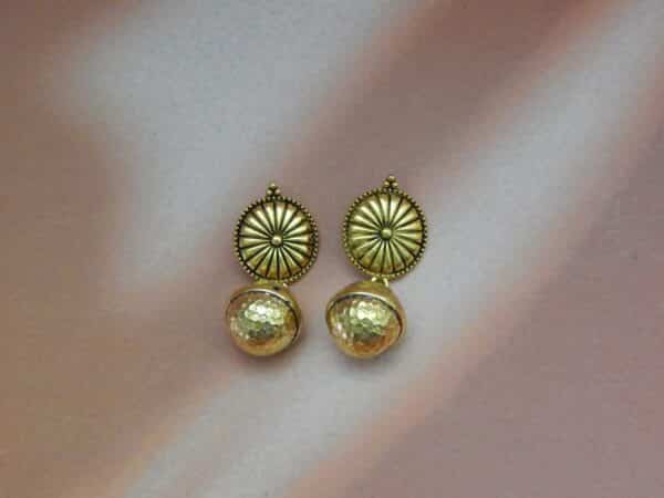 A pair of gold-toned ethnic earrings with a circular sunburst stud and a hammered bell-shaped dangle below