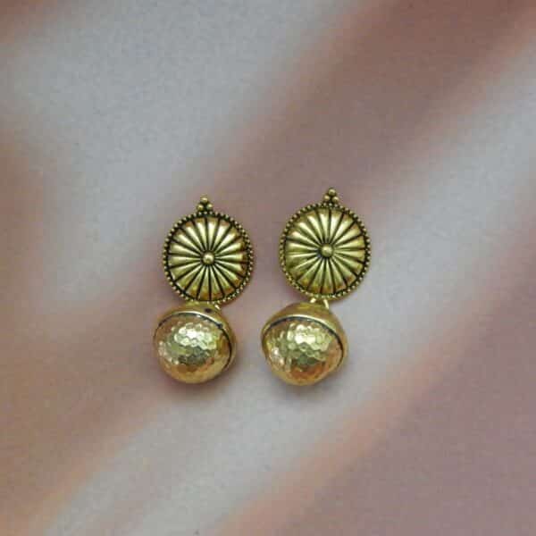 A pair of gold-toned ethnic earrings with a circular sunburst stud and a hammered bell-shaped dangle below