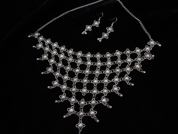 Wide German Silver choker necklace with mesh/net pattern of small oxidized floral links and matching hook earrings on a black background.