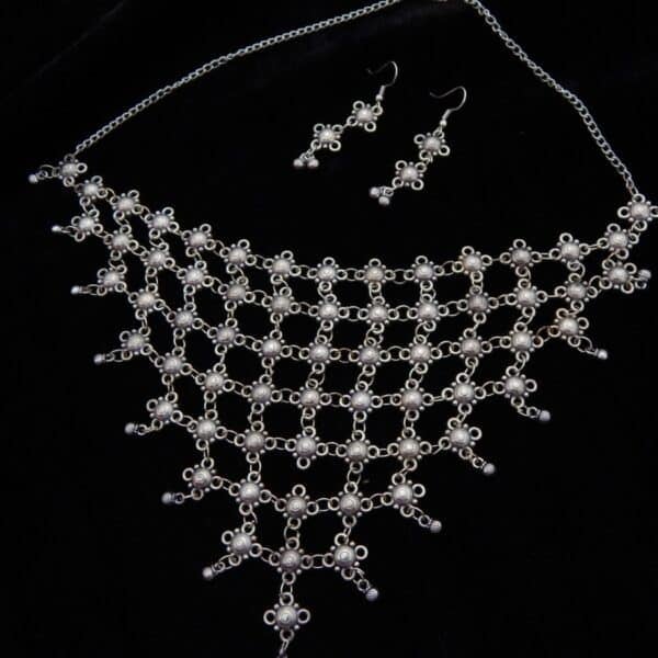 Wide German Silver choker necklace with mesh/net pattern of small oxidized floral links and matching hook earrings on a black background.