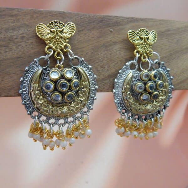 A pair of two-toned earrings featuring an oxidized silver and gold chandbali design with a peacock motif and small gold beaded drops.