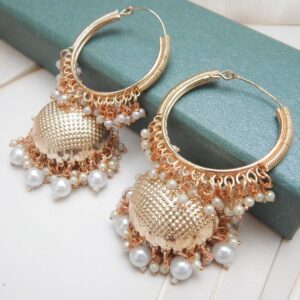 A pair of gold hoop jhumka earrings with white pearls, displayed on a red jewelry stand.