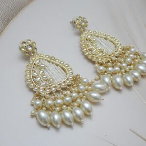 A pair of large, traditional dangle earrings in a teardrop shape with a filigree-like design, covered in small white pearls, and a fan of large pearl drops at the bottom.