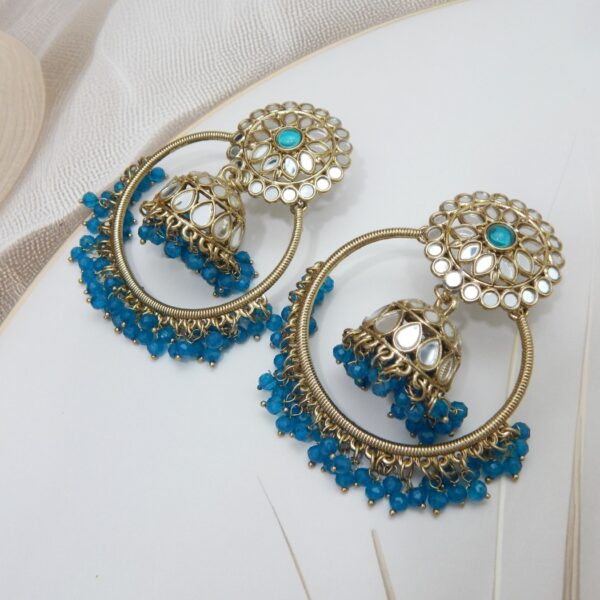 A pair of large, traditional hoop jhumka earrings with intricate mirror work on the top stud and bell, and a cluster of dangling blue colored beads on the bottom.