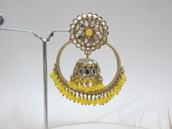 A pair of large, traditional hoop jhumka earrings with intricate mirror work on the top stud and bell, and a cluster of dangling yellow colored beads on the bottom.