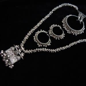 Full German Silver jewelry set featuring a long beaded necklace, an engraved rectangular peacock motif pendant with ghungroos, and matching oxidized jhumka hoops.