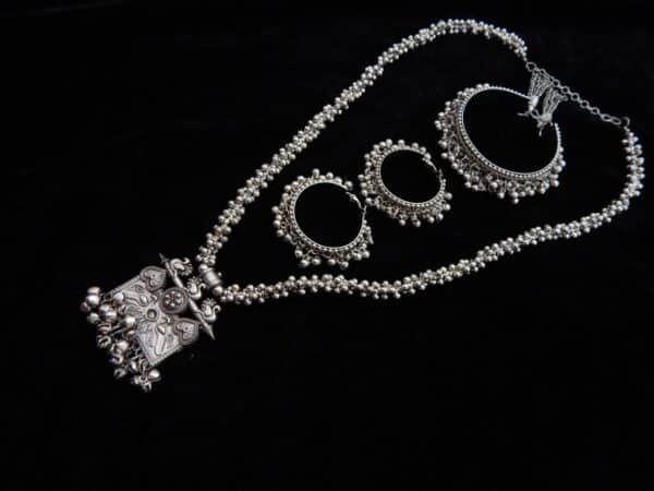 Full German Silver jewelry set featuring a long beaded necklace, an engraved rectangular peacock motif pendant with ghungroos, and matching oxidized jhumka hoops.
