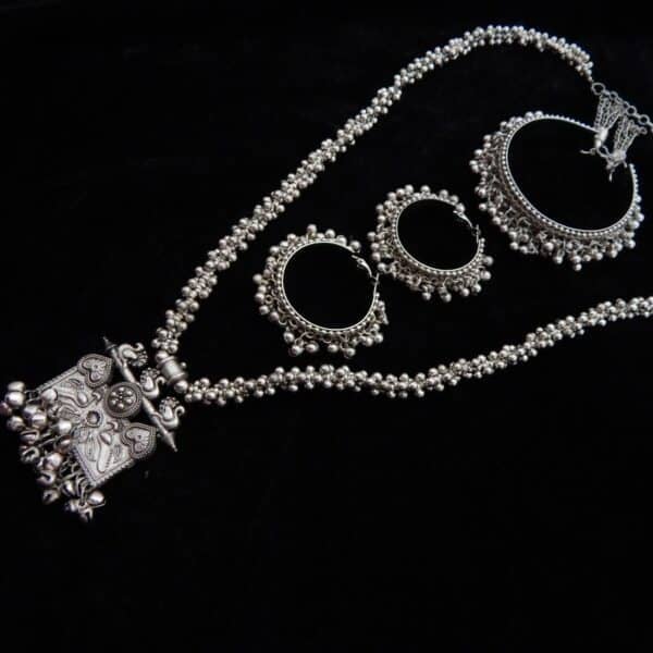 Full German Silver jewelry set featuring a long beaded necklace, an engraved rectangular peacock motif pendant with ghungroos, and matching oxidized jhumka hoops.