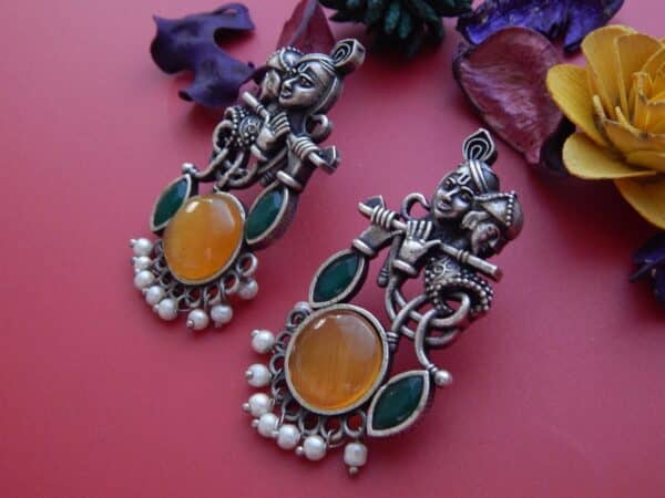 Radha Krishna dangler earrings in oxidised finish with amber cat eye stone