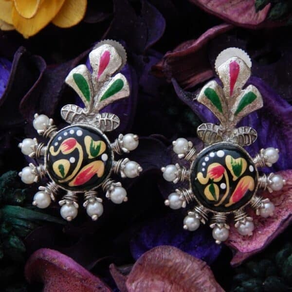 A pair of oxidized silver studs with a floral-shaped top, central green enamel floral work, and pearl bead accents.