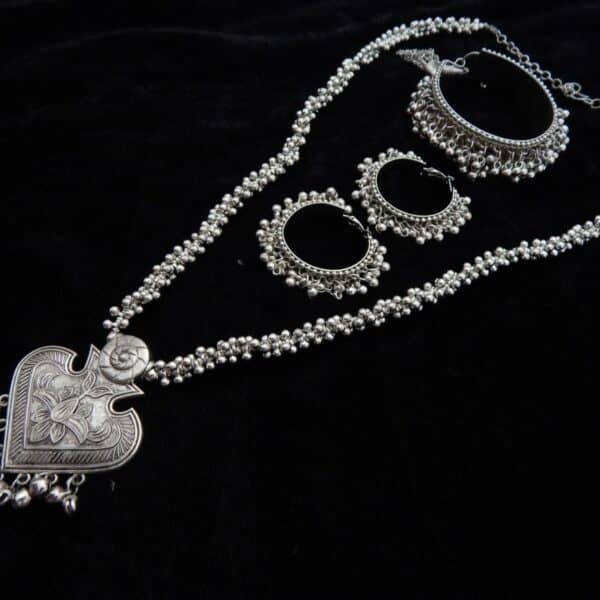 Full oxidized silver jewelry set including a long beaded necklace with a heart pendant and two pairs of matching jhumka hoops.