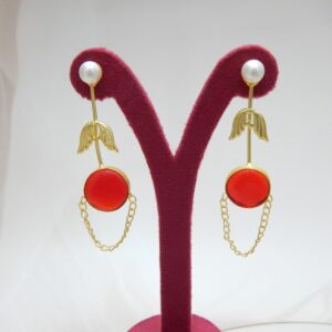 A pair of long gold-tone arrow-design earrings with a pearl stud, a round red colored stone, and a delicate chain loop.