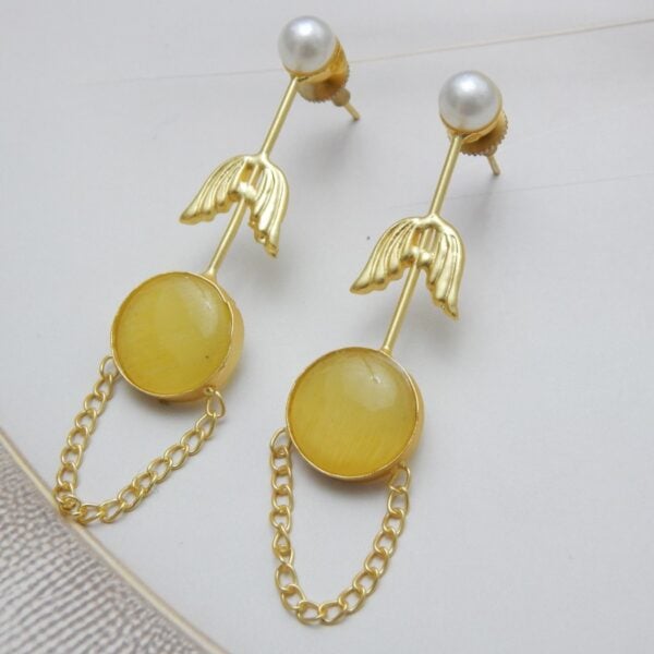 A pair of long gold-tone arrow-design earrings with a pearl stud, a round yellow colored stone, and a delicate chain loop.