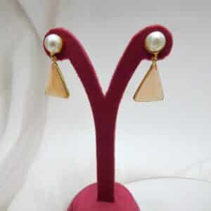 Gold and pearl stud earrings with a dangling, faceted peach-colored triangular stone.
