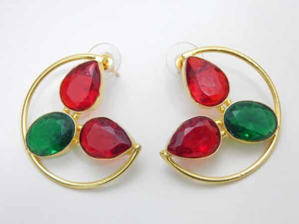Large gold-tone crescent earrings with two red teardrop stones and one green oval stone.