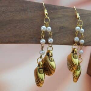 A pair of gold-toned dangle earrings with a chain of small white pearls and two seashell charms hanging from each