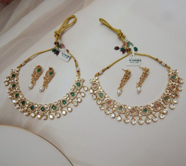 A traditional gold-toned Kundan necklace and earring set with a scalloped design, sparkling clear stones, and pink and green stones.