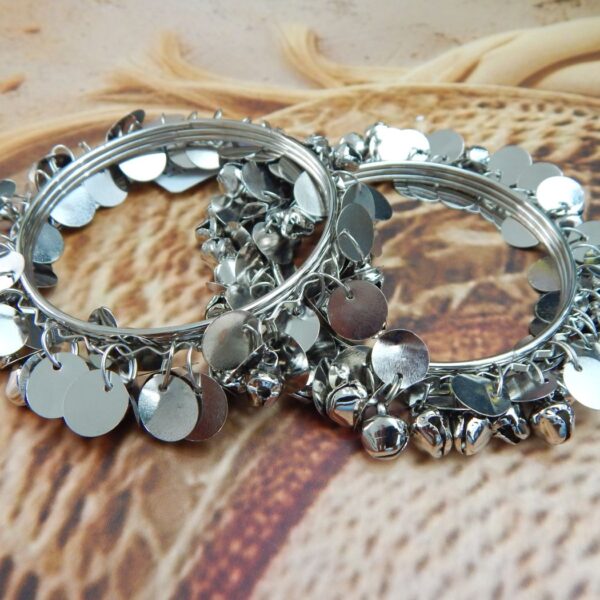 Pair of silver wire bangles adorned with tiny dangling ghungroo bells and circular coin charms, suitable for college students and festive wear.