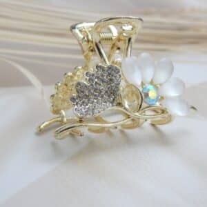 front view of Small gold-toned hair claw clip with clear rhinestones and opalescent white/off-white cat-eye flower petals, elegant hair accessory for women.