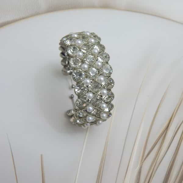 Wide, open-ended silver-toned cuff kada with large clear crystals and pearl beads set in a lattice pattern, high-end bridal jewelry.