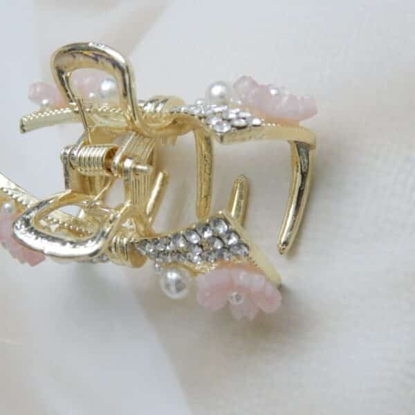 Navratri Purple Jewellery - Royal Reflection DS Small gold-toned hair claw clip with a crystal bow, pearl beads, and small pink resin flowers, elegant hair accessory for women.