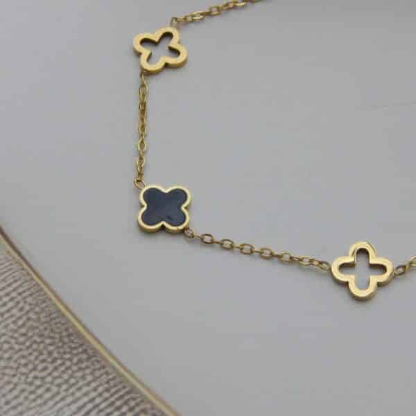 Close-up of four-leaf clover charm bracelet in gold and black enamel – Royal Reflection Dazzling Studio.