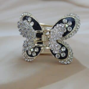 Large butterfly-shaped hair claw clip in a gold tone with black enamel and clear sparkling rhinestone studs, elegant hair accessory.