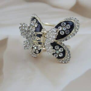 Large butterfly-shaped hair claw clip in a gold tone with black enamel and clear sparkling rhinestone studs, elegant hair accessory.