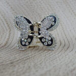 Large butterfly-shaped hair claw clip in a gold tone with black enamel and clear sparkling rhinestone studs, elegant hair accessory.