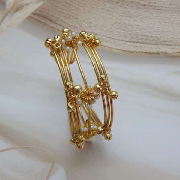Multi-strand gold-plated kada/cuff with dangling ghungroos and small white pearls, designed in a traditional temple style.