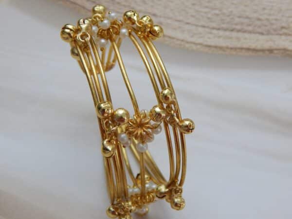 Multi-strand gold-plated kada/cuff with dangling ghungroos and small white pearls, designed in a traditional temple style.