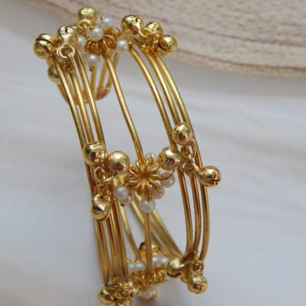 Multi-strand gold-plated kada/cuff with dangling ghungroos and small white pearls, designed in a traditional temple style.