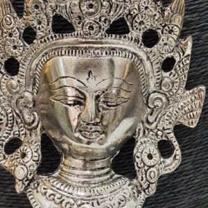 Close-up of oxidised goddess face pendant necklace with ornate crown and devotional motifs