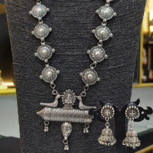 Oxidised long necklace set with round motifs and peacock pendant paired with jhumka earrings on display stand
